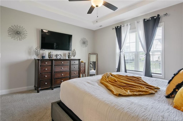 carpeted bedroom with ceiling fan, baseboards, visible vents, and a raised ceiling