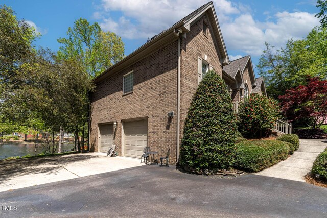 955 Sagamore Dr, Louisburg, NC 27549 - view of property exterior with an attached garage, driveway, a water view, and brick siding
