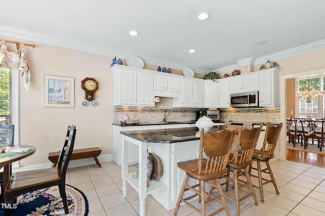 955 Sagamore Dr, Louisburg, NC 27549 - kitchen featuring crown molding, light tile patterned floors, stainless steel microwave, a sink, and backsplash