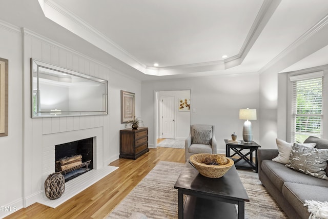 4902 Brookhaven Dr, Raleigh, NC 27612 - living area with ornamental molding, light wood-type flooring, a brick fireplace, a tray ceiling, and baseboards