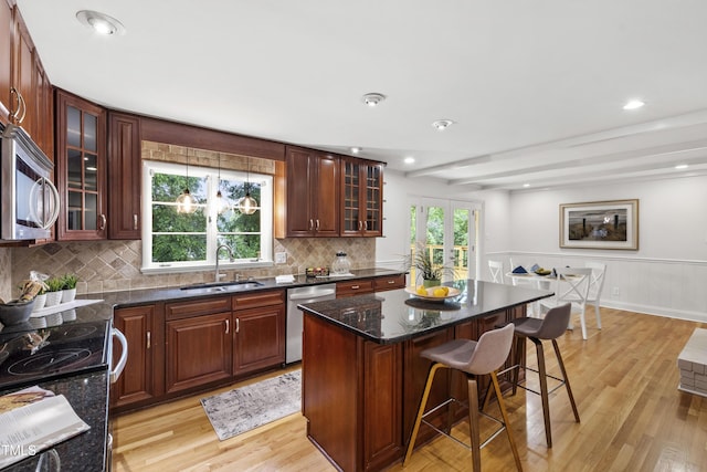 4902 Brookhaven Dr, Raleigh, NC 27612 - kitchen with a sink, stainless steel appliances, light wood-type flooring, a breakfast bar, and a center island