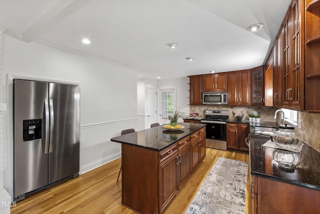 4902 Brookhaven Dr, Raleigh, NC 27612 - kitchen featuring stainless steel appliances, a sink, light wood-style flooring, dark stone counters, and wainscoting
