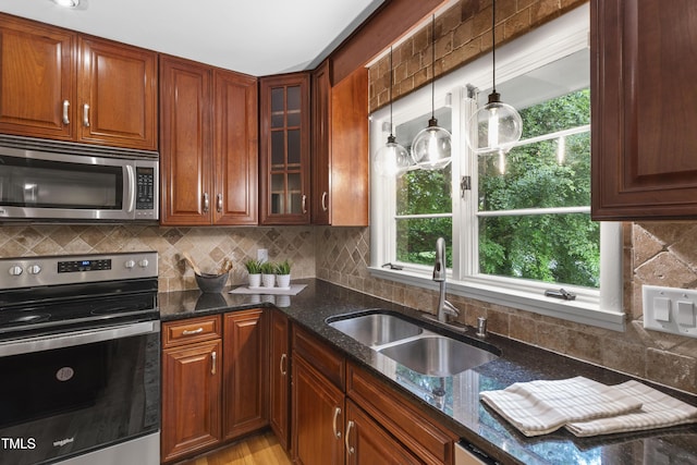 4902 Brookhaven Dr, Raleigh, NC 27612 - kitchen featuring stainless steel appliances, a sink, dark stone counters, decorative backsplash, and glass insert cabinets