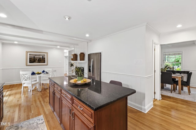 4902 Brookhaven Dr, Raleigh, NC 27612 - kitchen with stainless steel fridge, light wood-style floors, a center island, dark stone countertops, and a wainscoted wall