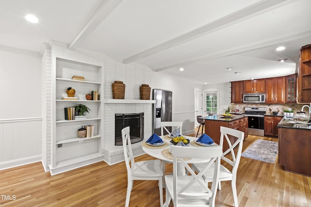 4902 Brookhaven Dr, Raleigh, NC 27612 - dining area with light wood finished floors, beam ceiling, and a brick fireplace