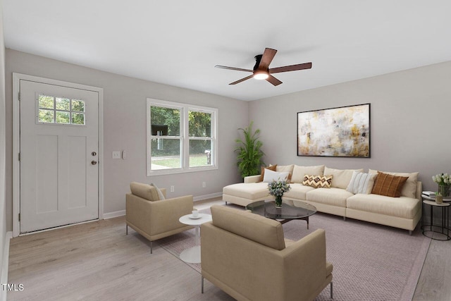 living room featuring a ceiling fan, baseboards, a healthy amount of sunlight, and light wood-type flooring