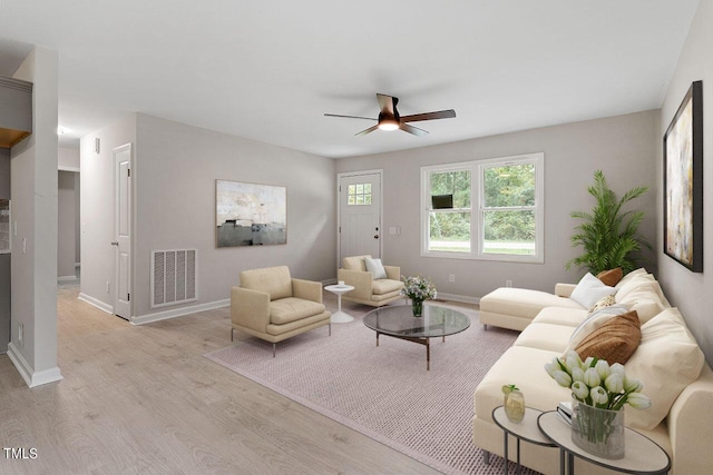 living room featuring light wood-type flooring, baseboards, a ceiling fan, and visible vents