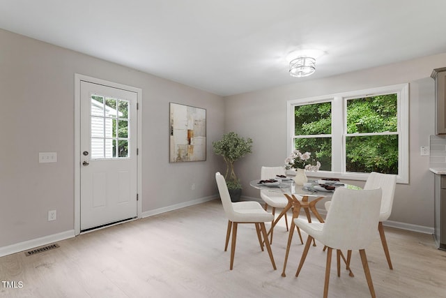 dining space with light wood-style floors, visible vents, and baseboards