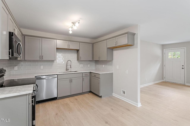 kitchen with light wood-style flooring, gray cabinetry, stainless steel appliances, and a sink