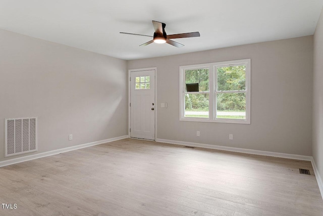 empty room with baseboards, a ceiling fan, visible vents, and light wood-style floors