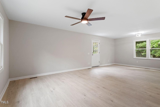 empty room with ceiling fan, a wealth of natural light, baseboards, and light wood-style flooring