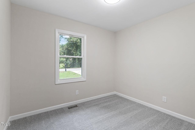 empty room with baseboards, visible vents, and carpet