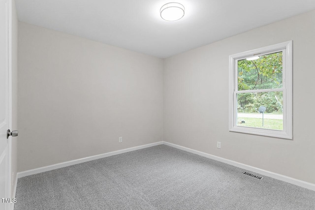 spare room with carpet, visible vents, and baseboards