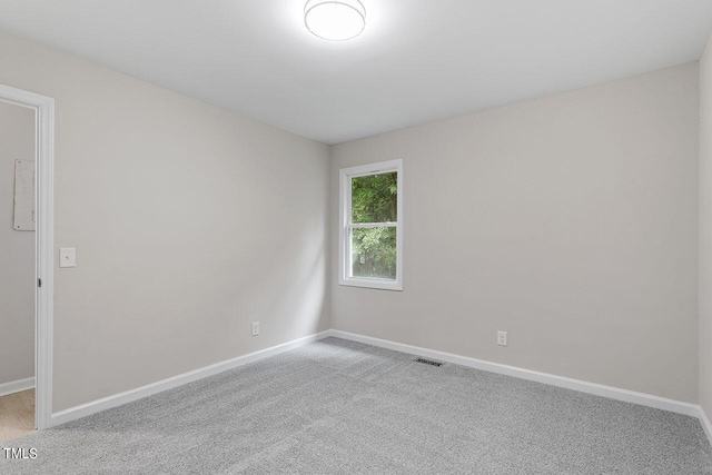 spare room featuring light colored carpet, baseboards, and visible vents