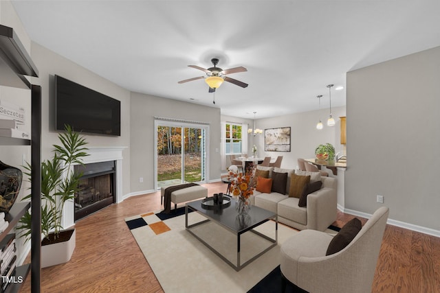 219 Zante Currant Rd, Durham, NC 27703 - living room featuring a fireplace, light wood-style flooring, ceiling fan with notable chandelier, and baseboards