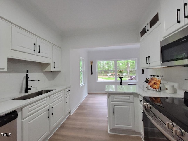 kitchen with appliances with stainless steel finishes, a sink, and white cabinetry