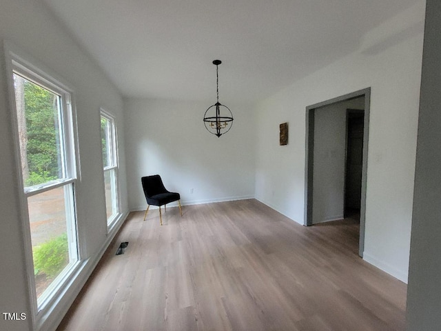 unfurnished dining area featuring plenty of natural light, light wood-style floors, a chandelier, and baseboards