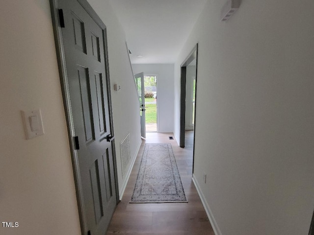 hallway featuring wood finished floors and baseboards
