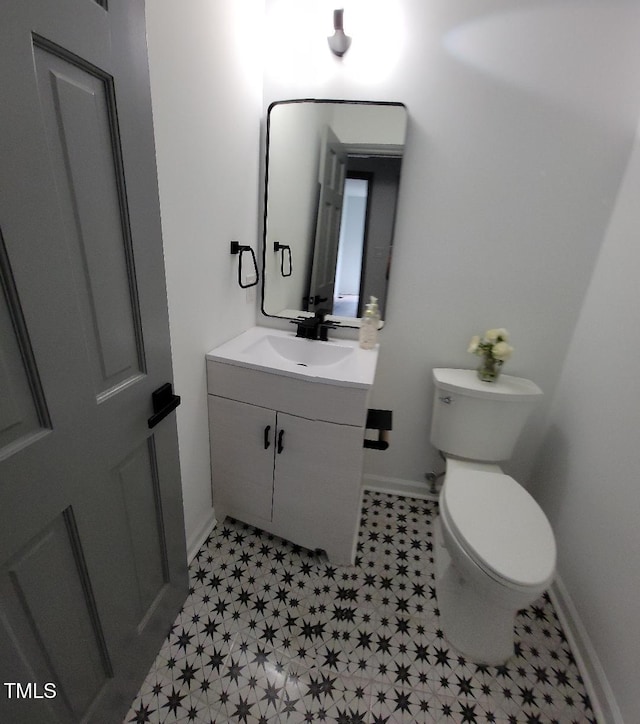 bathroom featuring toilet, vanity, and baseboards