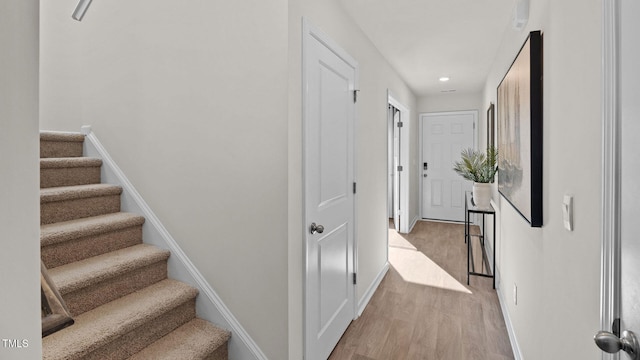 stairs featuring wood finished floors, baseboards, and recessed lighting