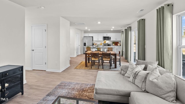 living area featuring recessed lighting, light wood-style floors, baseboards, and visible vents