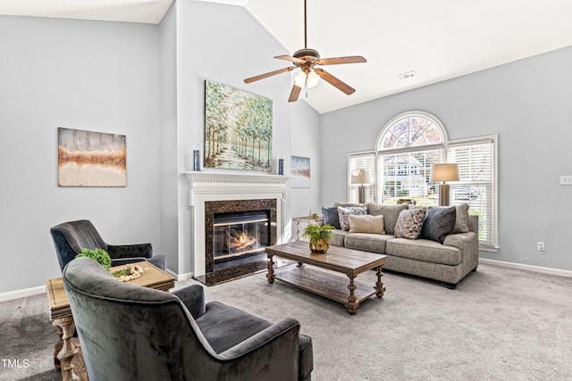 carpeted living room with baseboards, a fireplace, a ceiling fan, visible vents, and high vaulted ceiling