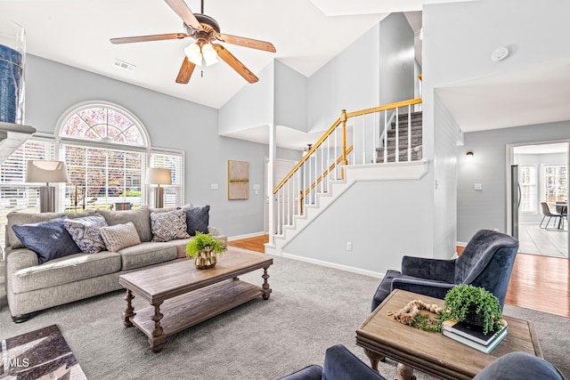 carpeted living area with visible vents, a ceiling fan, and stairs