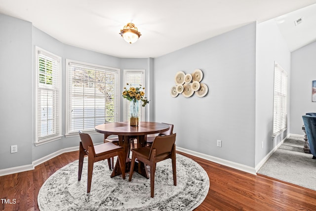 dining space with dark wood-type flooring, visible vents, and baseboards