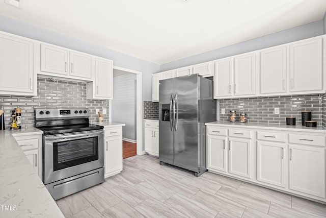 kitchen with appliances with stainless steel finishes, light stone counters, backsplash, and white cabinets