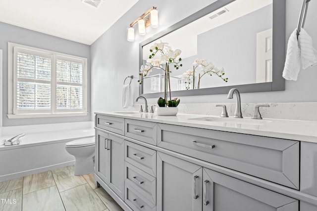 full bathroom featuring a garden tub, double vanity, a sink, and visible vents