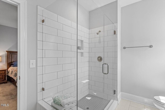 bathroom with toilet, connected bathroom, a stall shower, and baseboards