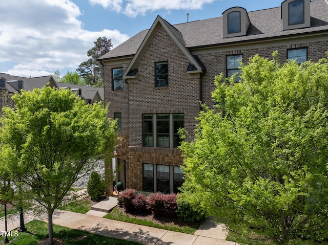view of front of house with brick siding and a shingled roof