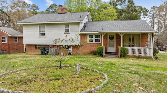 view of front of home featuring a front yard, a porch, brick siding, and a chimney