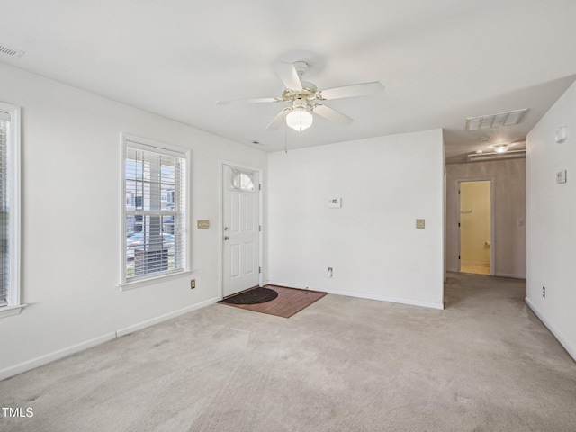 carpeted foyer featuring a ceiling fan and baseboards