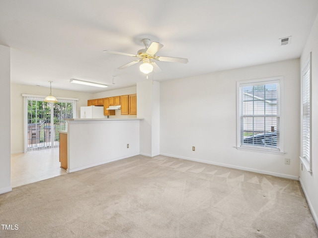unfurnished living room with light colored carpet, a ceiling fan, and baseboards