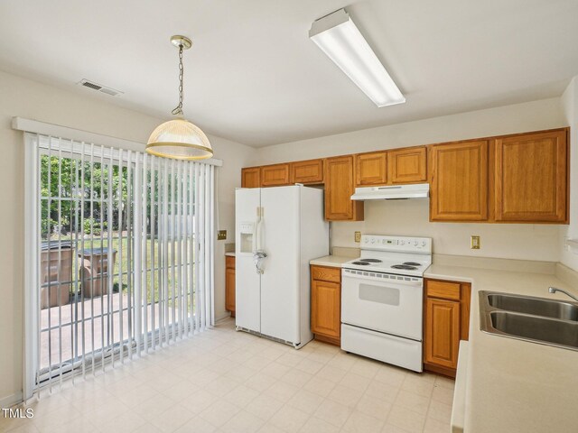 kitchen featuring white appliances, under cabinet range hood, a sink, brown cabinetry, and light countertops