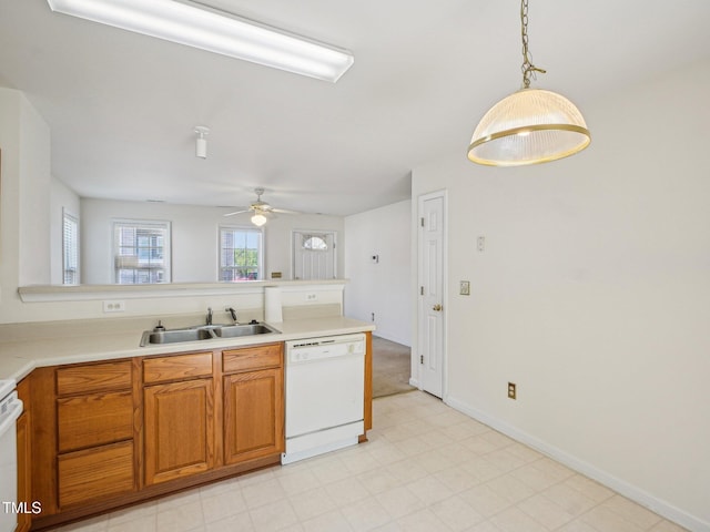 kitchen with white dishwasher, a sink, a peninsula, brown cabinets, and a ceiling fan