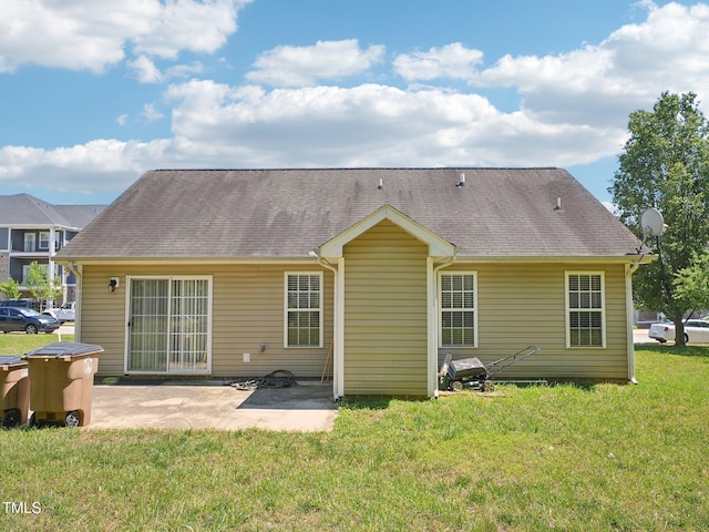 back of property with a patio area, a lawn, and a shingled roof