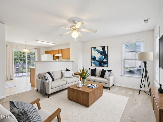 living area with light colored carpet, baseboards, and ceiling fan