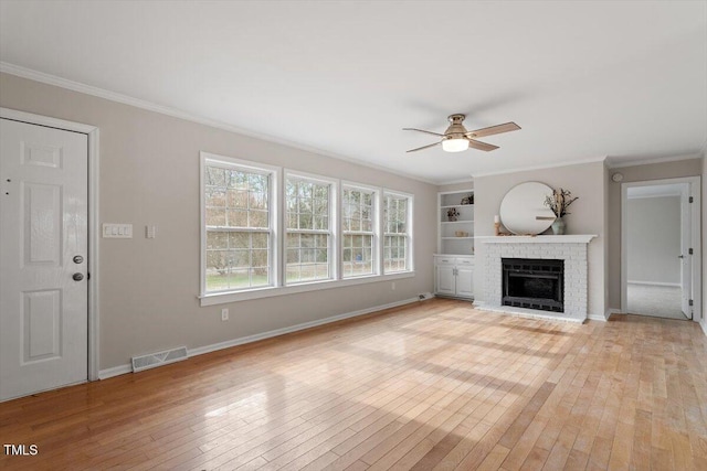 unfurnished living room with visible vents, light wood-type flooring, a ceiling fan, and crown molding