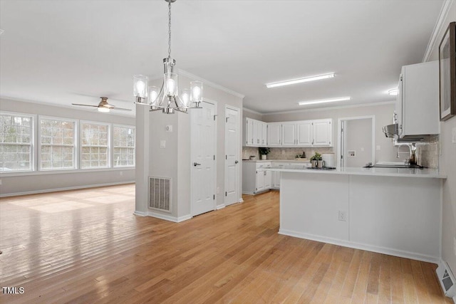 kitchen with visible vents, backsplash, white cabinetry, and light wood-style floors