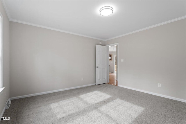 carpeted spare room featuring visible vents, baseboards, and ornamental molding