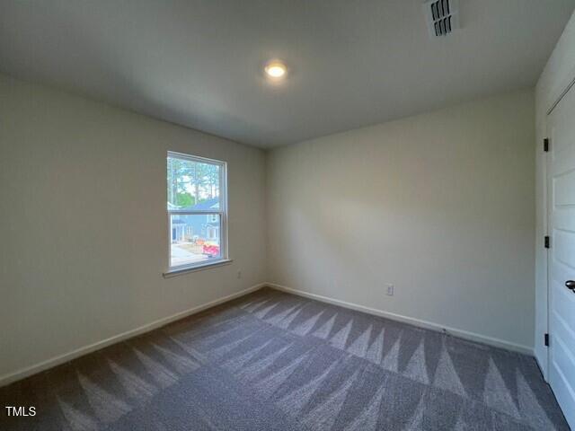 carpeted spare room featuring baseboards and visible vents