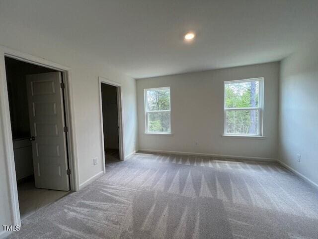 unfurnished bedroom with carpet, multiple windows, and baseboards