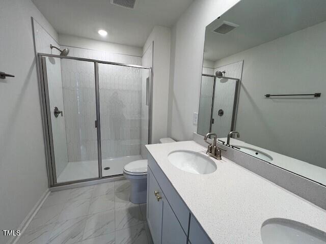 full bathroom featuring toilet, a stall shower, marble finish floor, and a sink