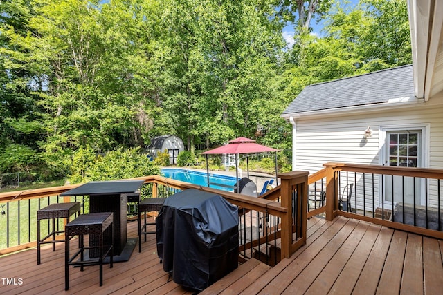 wooden deck with a storage shed, an outdoor structure, an outdoor pool, and a grill