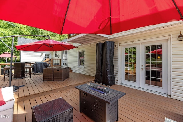 wooden deck with an outdoor fire pit, french doors, and outdoor dining area