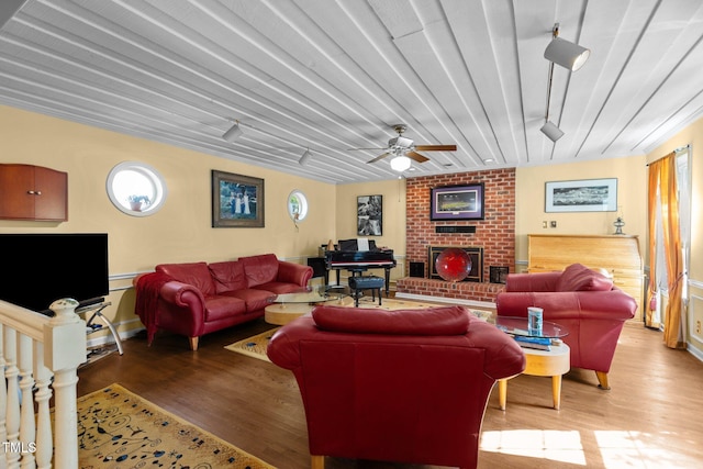 living room with a fireplace, light wood-style flooring, and a ceiling fan