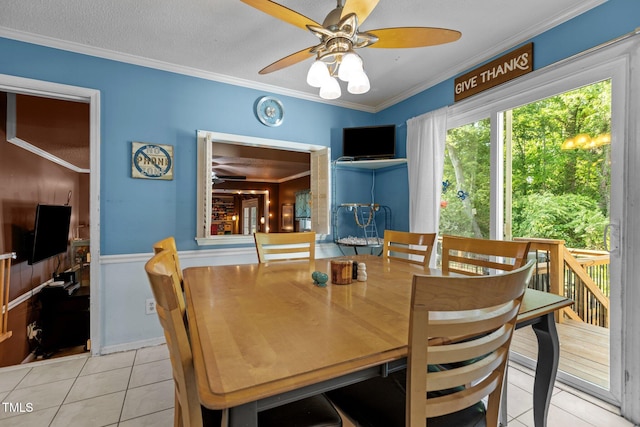 tiled dining area with ceiling fan, ornamental molding, and wainscoting