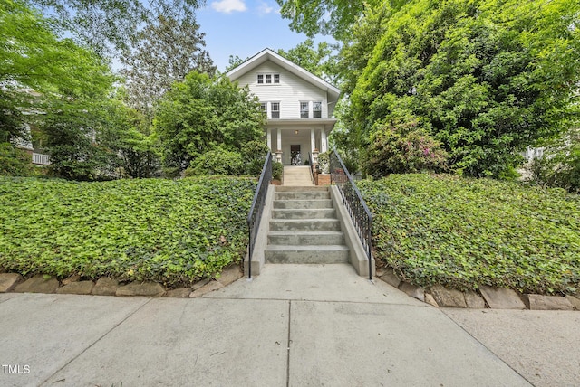 view of front of property featuring covered porch and stairway